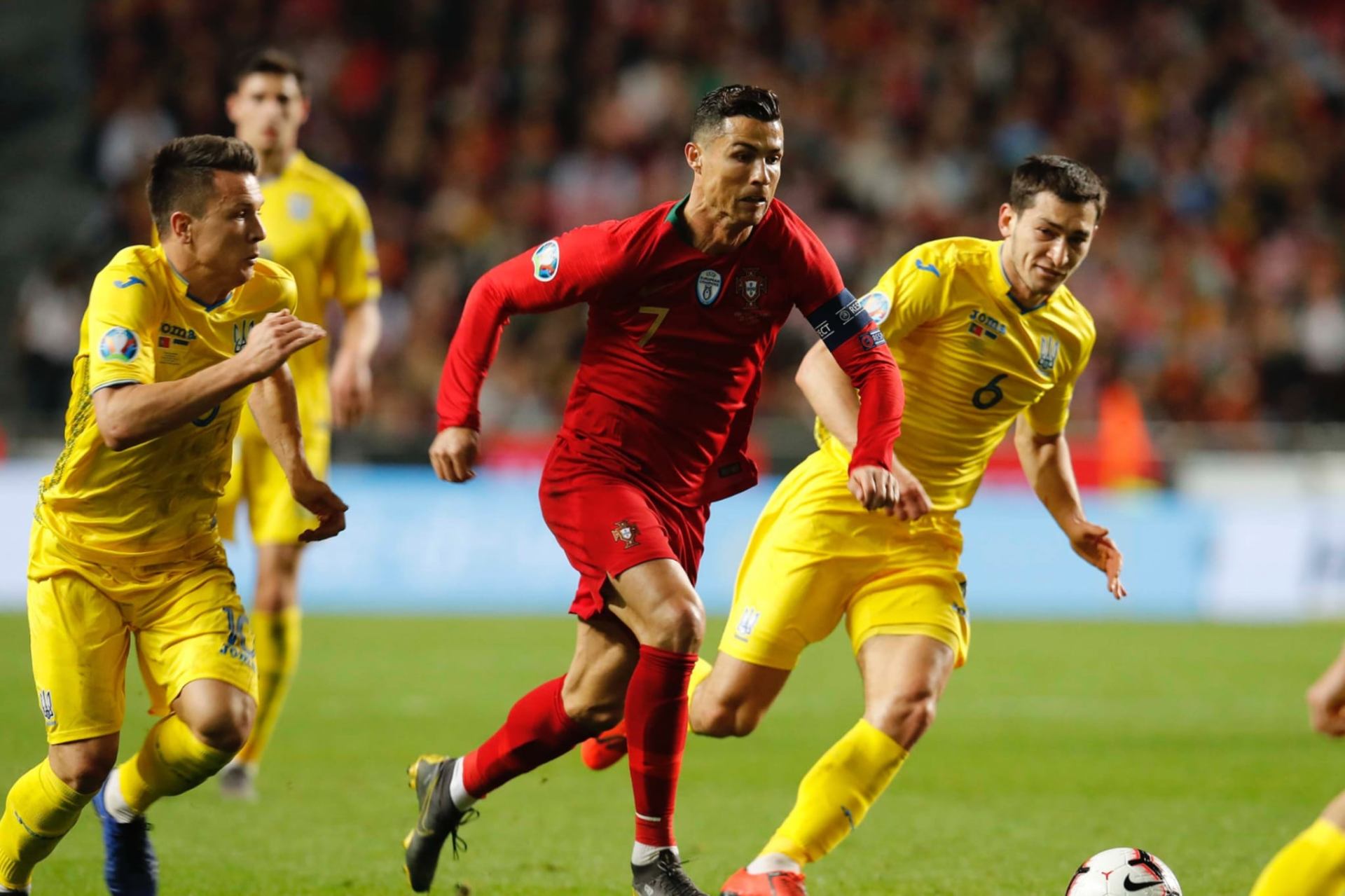 Cristiano Ronaldo em campo pela Seleção Portuguesa a driblar dois adversários